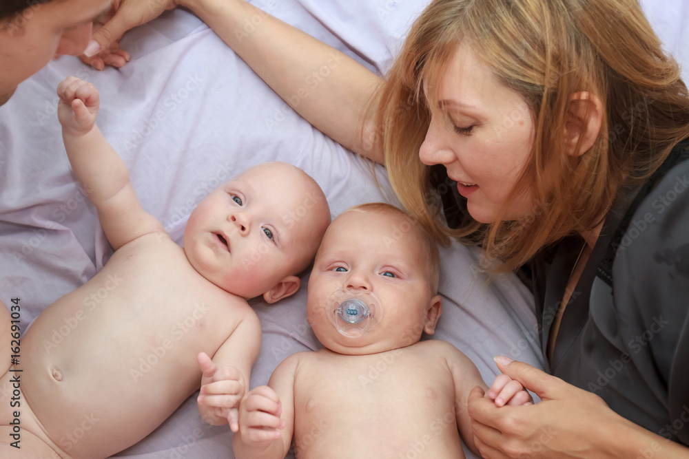 indoor portrait of young beautiful mother and father with baby, family with twins at home indoor portrait of young beautiful mother and father with baby, family with twins at home