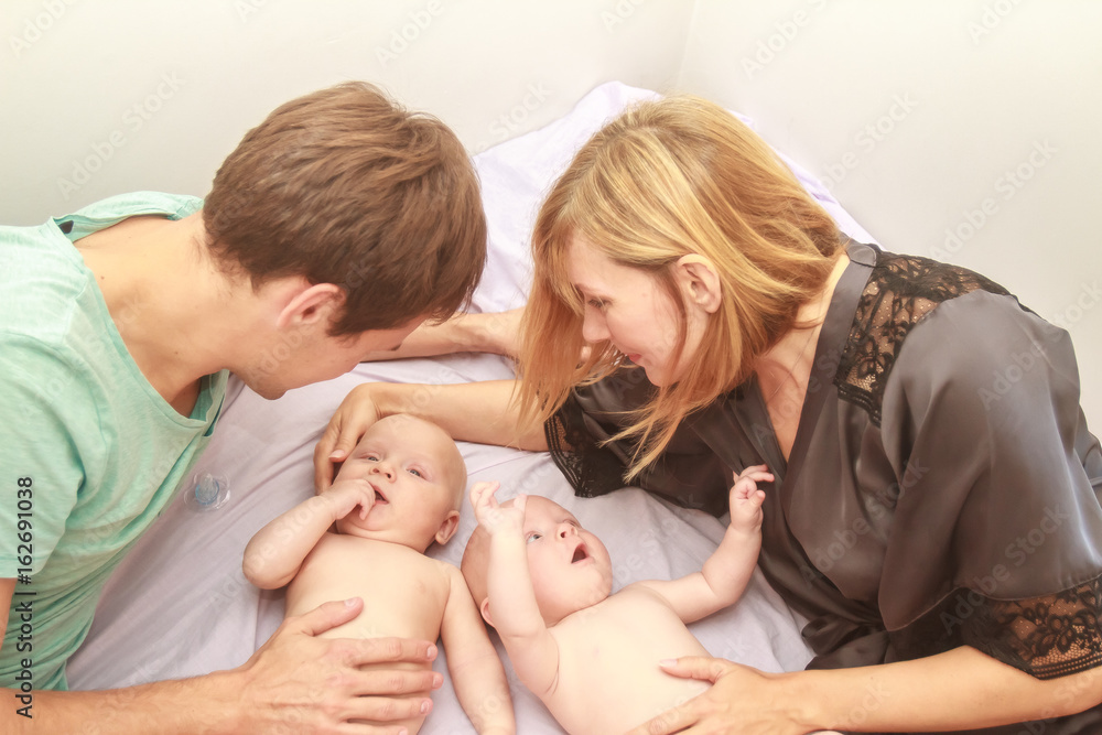 indoor portrait of young beautiful mother and father with baby, family with twins at home indoor portrait of young beautiful mother and father with baby, family with twins at home