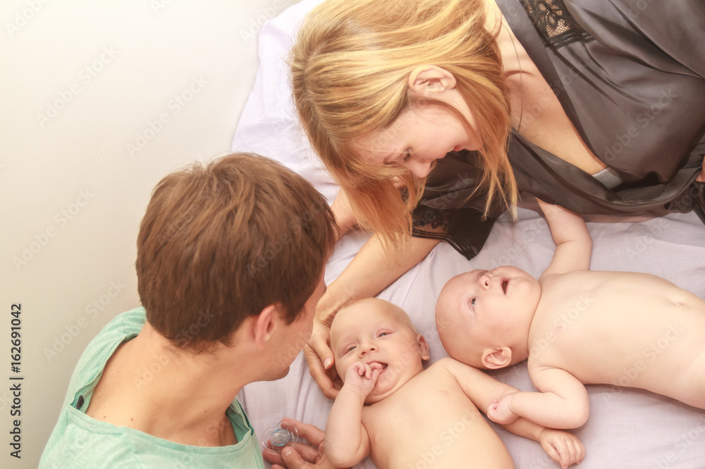 indoor portrait of young beautiful mother and father with baby, family with twins at home indoor portrait of young beautiful mother and father with baby, family with twins at home