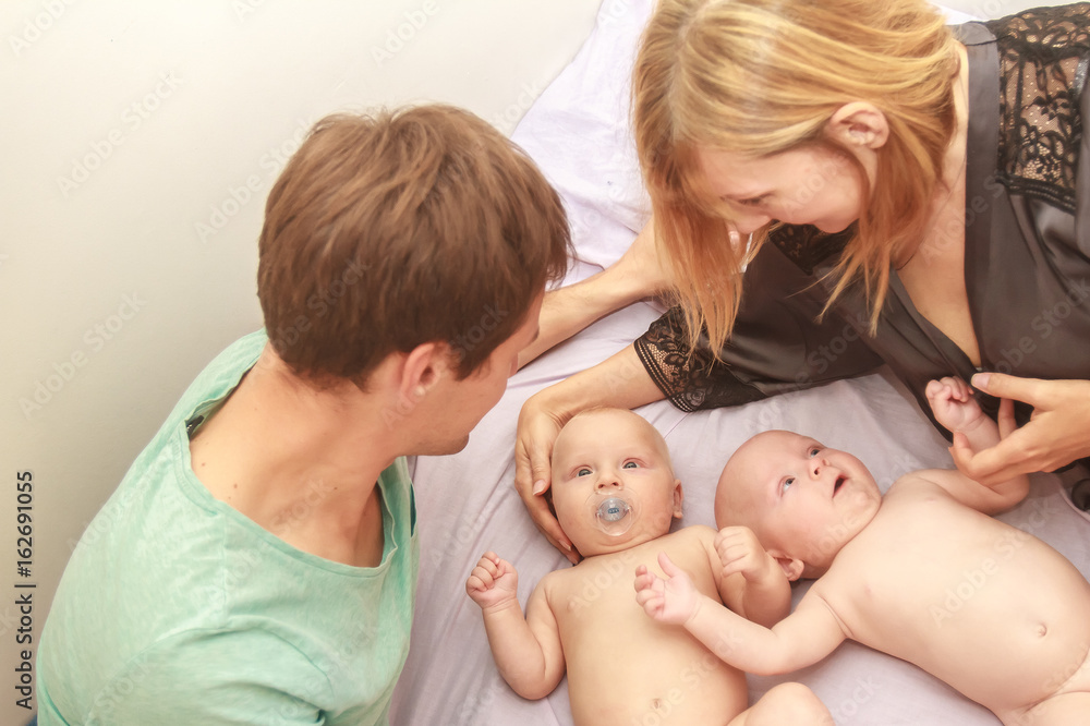 indoor portrait of young beautiful mother and father with baby, family with twins at home indoor portrait of young beautiful mother and father with baby, family with twins at home