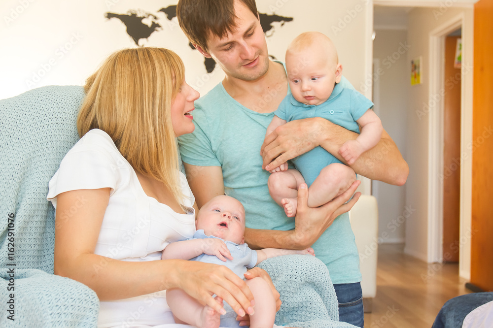 indoor portrait of young beautiful mother and father with baby, family with twins at home indoor portrait of young beautiful mother and father with baby, family with twins at home