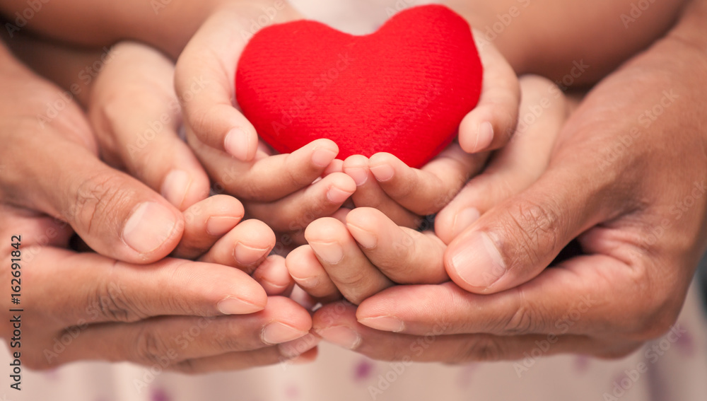 Red heart in child kid mother and father hands in vintage color tone. love,care and family concept Red heart in child kid mother and father hands in vintage color tone. love,care and family concept