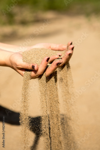 sand running through hands of woman