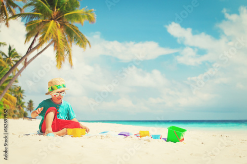 Fototapeta Naklejka Na Ścianę i Meble -  little boy play with sand and toys on beach
