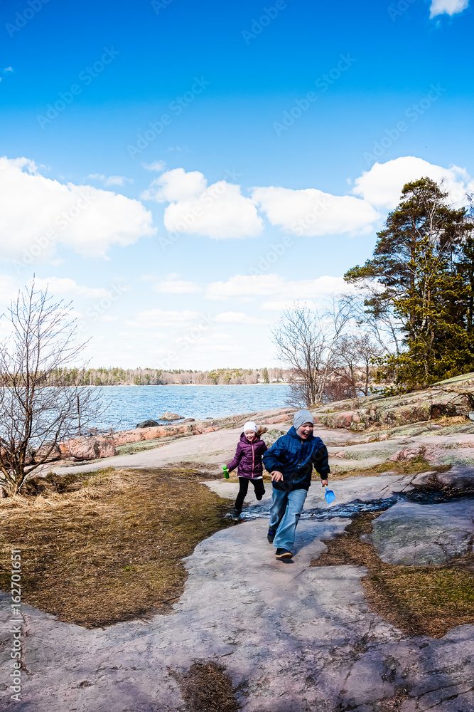 Children walk along the lake shore in spring