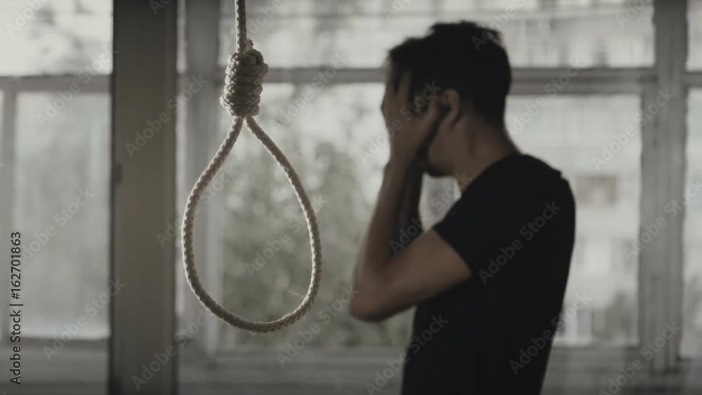 Suicide. Depressed man crying on the background of the loop for the neck.
