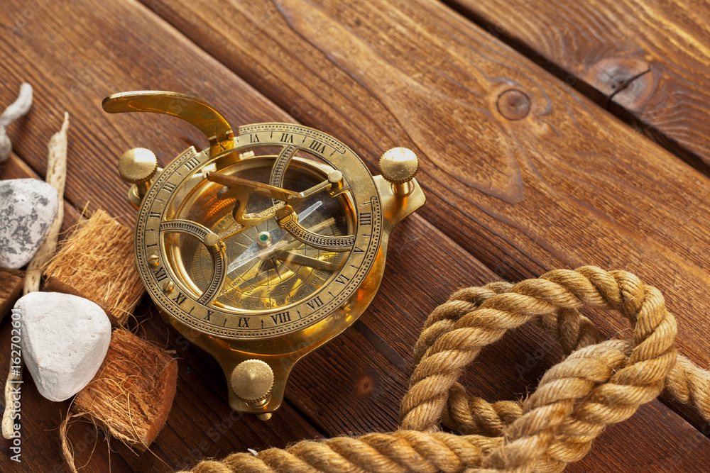 Fototapeta premium Compass and rope on wooden table. close up