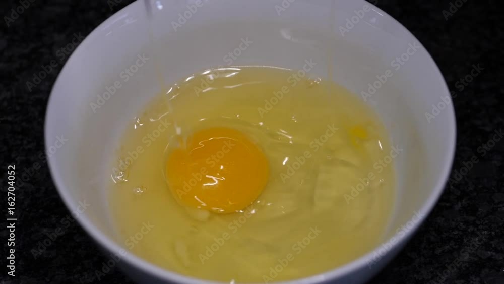 Slow motion of woman cracking egg inside bowl Slow motion of woman cracking egg inside bowl