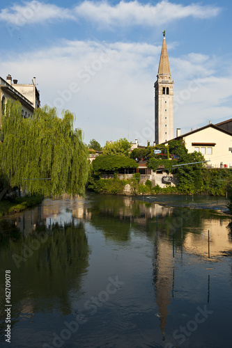 The cathedral of San Nicol   is reflected on Livenza river in Sacile. Italy
