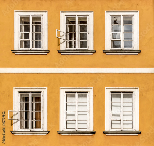 Six  windows in two rows with white frames. Building is of orange color situated in Prague.