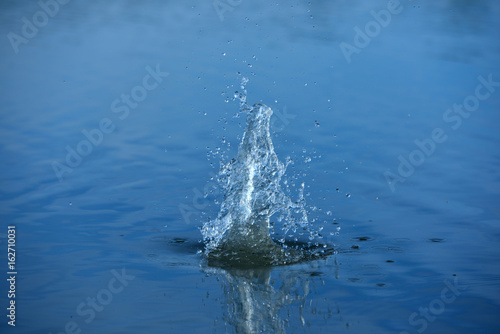 Spray of water from a thrown stone into the water