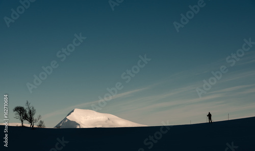 Arctic landscape with cross country skier and Tromsdalstiden mountain near Tromso ( Tromsø ), Norway