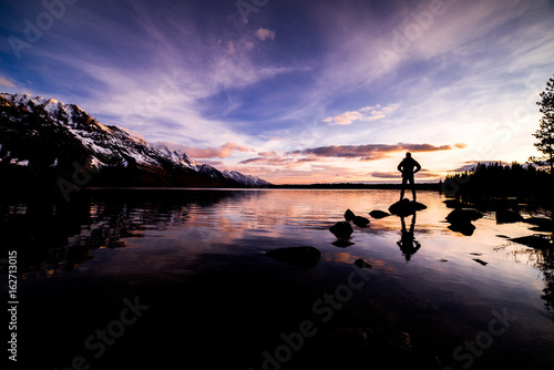 Sunrise on Jenny Lake with stunning colors and a person standing on a Rock Silhouetted