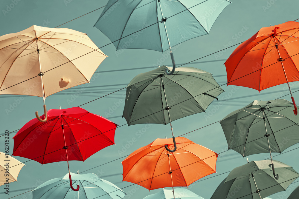 Obraz premium Multi-colored umbrellas in sky above the street. Alley floating umbrellas