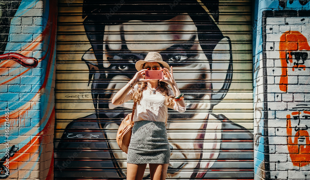 Naklejka premium Turysta bierze fotografię graffiti ściana z graffiti w tle w Melbourne, Australia.