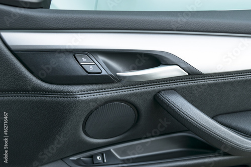 Car door handle inside the luxury modern car with black leather and switch button control, modern car interior details