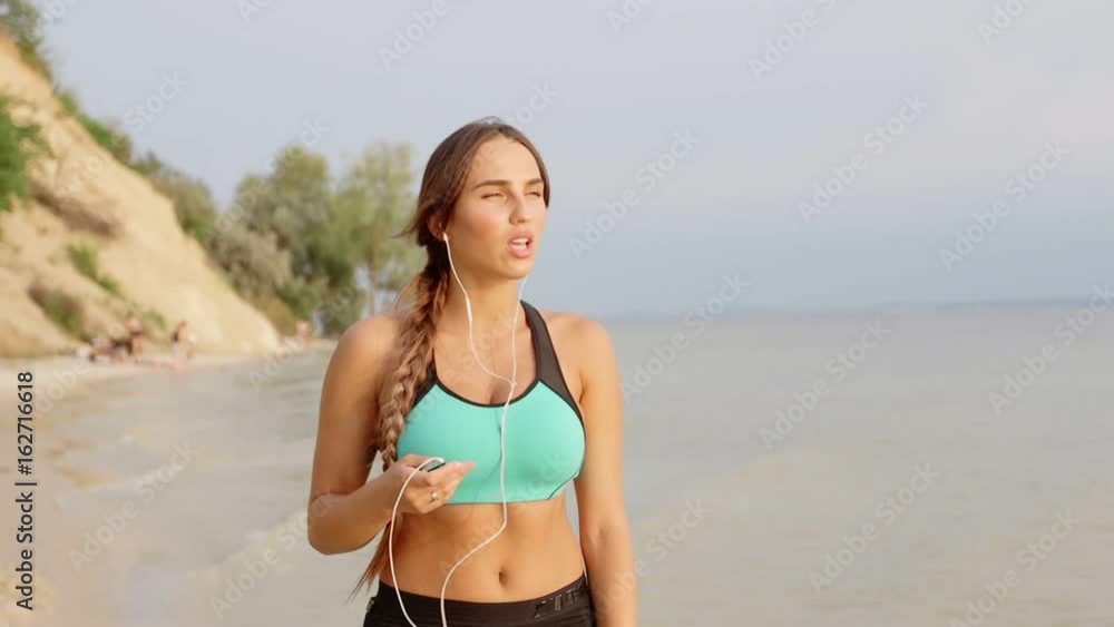 Fitness sport woman doing sporty exercise on beach outside at sunset. Healthy lifestyle image of beautiful young asian woman jogging on black sand beach. Fitness sport woman doing sporty exercise on beach outside at sunset. Healthy lifestyle image of beautiful young asian woman jogging on black sand beach.