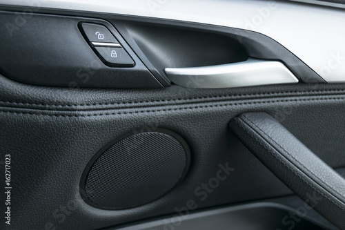 Car door handle inside the luxury modern car with black leather and switch button control, modern car interior details. Car detailing