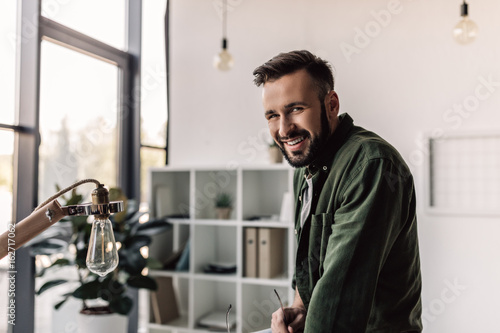 bearded businessman in casual clothing smiling at camera in modern office