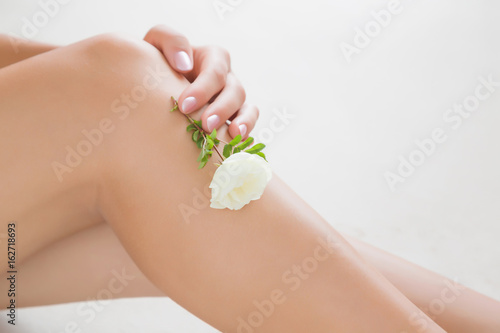 Woman s cares about a soft skin with body creams  lotions or oils in the bathroom after shower and shaving. Fresh white rose s gentle touch and scent.