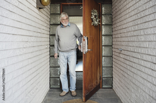 Full length of senior man opening wooden door photo