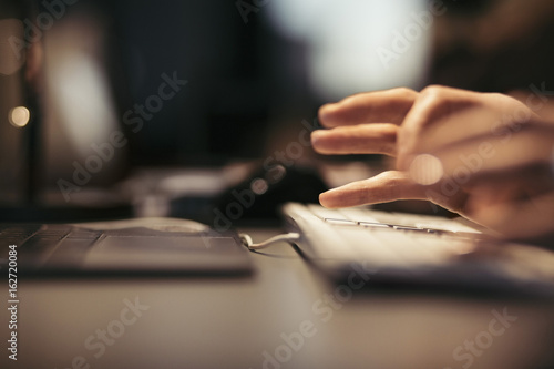 Cropped image of businesswoman using computer keyboard at desk in office photo