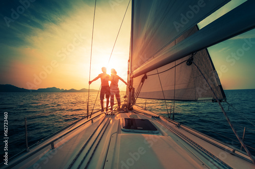 Young couple enjoys sunset from the sailing boat moving in the tropical sea © Dudarev Mikhail
