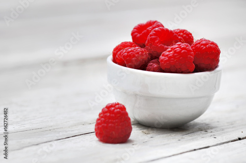 petit bol de framboise sur planche en bois blanc  photo