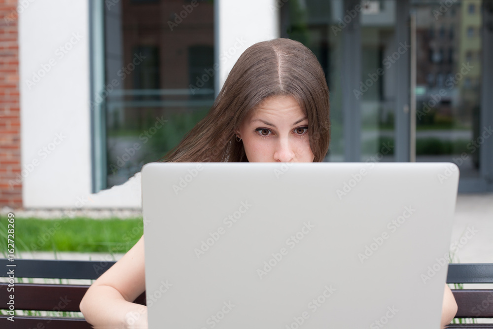 Young woman freelancer works with new silver laptop Young woman freelancer works with new silver laptop