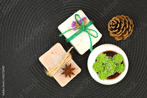 Organic handmade soaps decoration by pinecone  dry flowers  star anise and Succulent plant on black mat with copy space