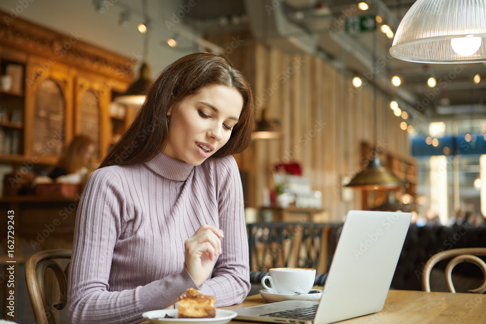 Beautiful brunette using laptop in cafe. Blogger work concept Beautiful brunette using laptop in cafe. Blogger work concept