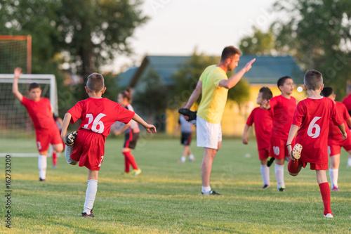 Fototapeta Naklejka Na Ścianę i Meble -  Kids soccer football - children players exercising before match on soccer field