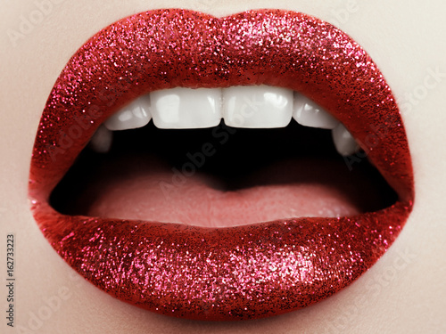 Glamour fashion bright red lips make-up with glitter. Macro of woman's face part. Sexy glossy lip makeup, luxury lady