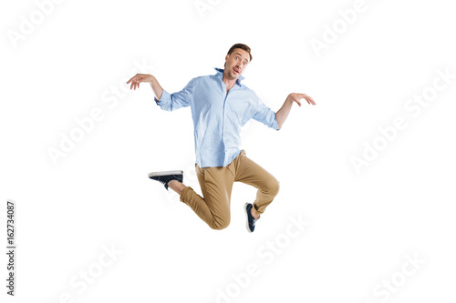 young casual man jumping with funny expression isolated on white