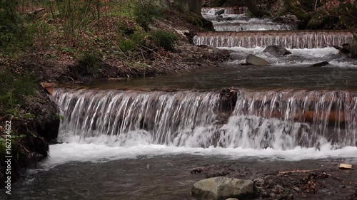 Mountain river with waterfalls and rapids flowing between rocky banks photo