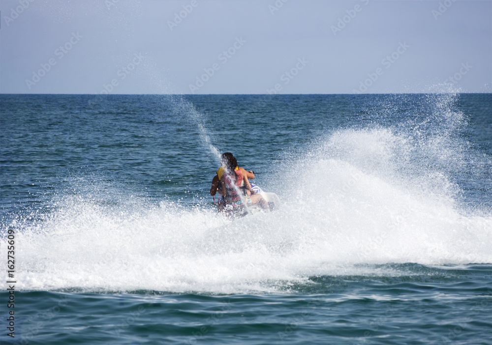 Happy young couple riding jet ski in speed on sea Happy young couple riding jet ski in speed on sea