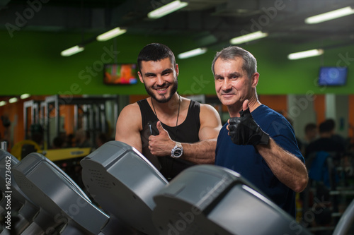 Senior man working on treadmill with trainer
