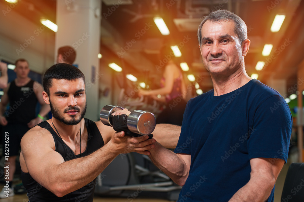 Smiling senior man and his personal trainer in gym Smiling senior man and his personal trainer in gym