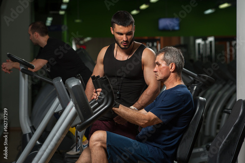 Senior man exercising on machinein gym