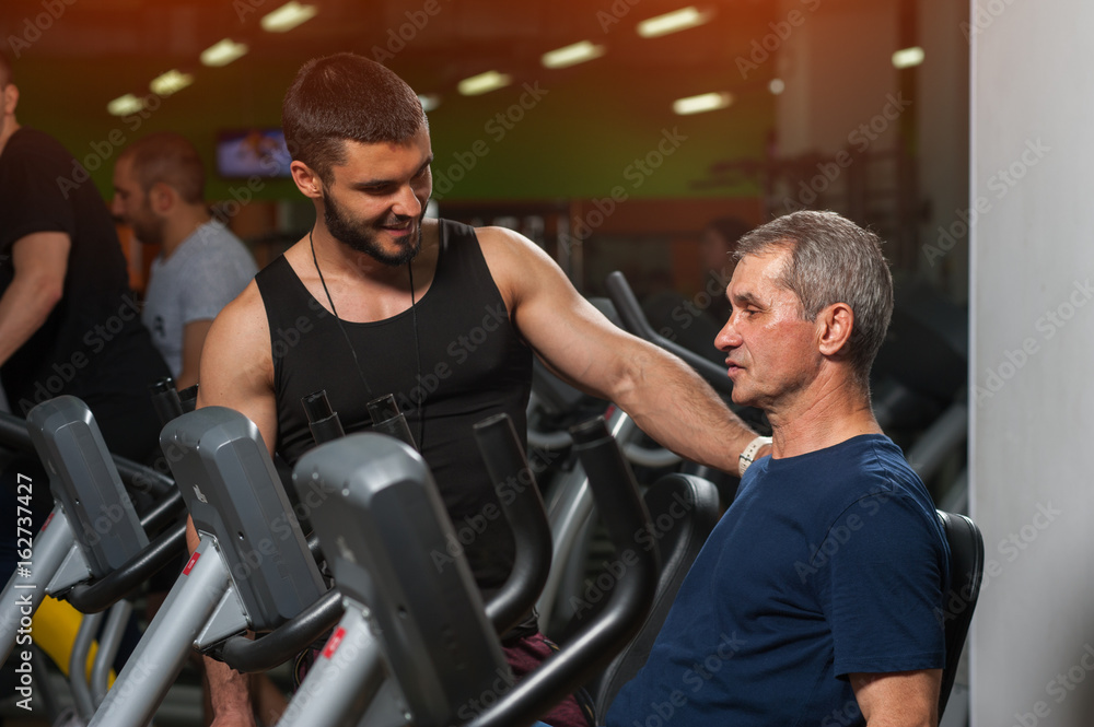 Senior man working with personal trainer in gym. Senior man working with personal trainer in gym.