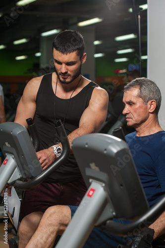 Personal trainer working with senior man in gym