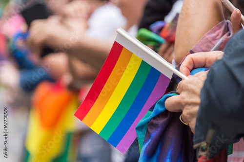 Gay Pride Parade spectator holding small gay rainbow flag during Toronto Pride Parade in 2017