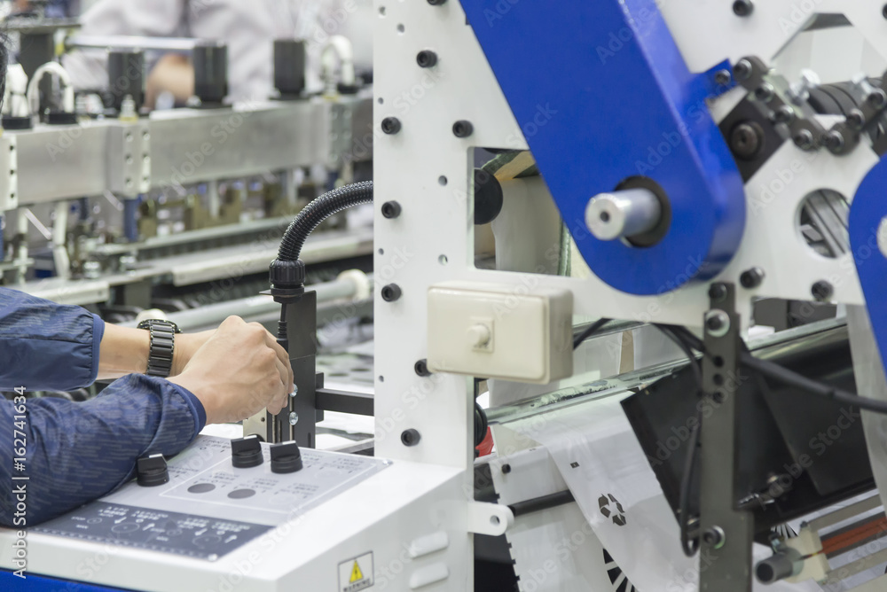 The technician adjust the printing machine.The plastic bag manufacturing process. The technician adjust the printing machine.The plastic bag manufacturing process.