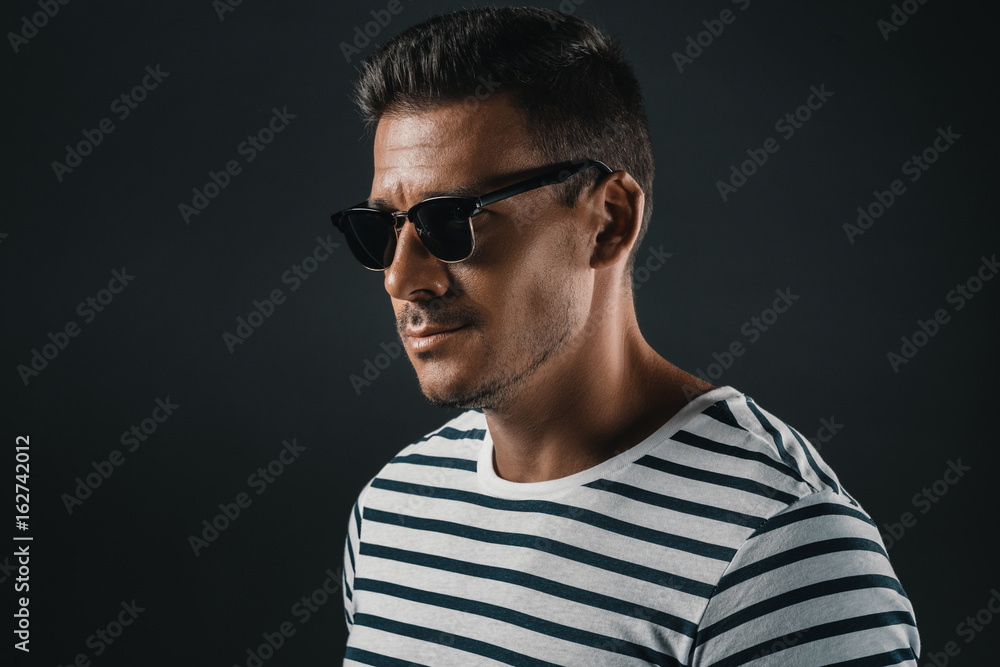 Obraz premium portrait of stylish man in striped t-shirt and sunglasses, isolated on grey