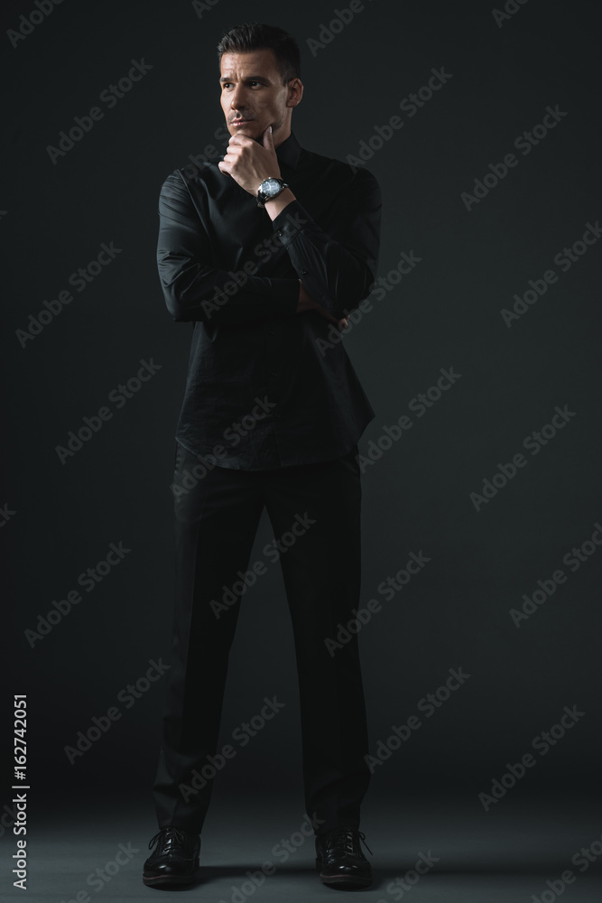 confident stylish man standing in black outfit, isolated on grey confident stylish man standing in black outfit, isolated on grey