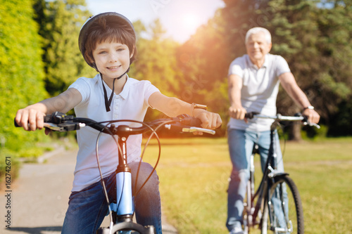 Young enthusiastic boy riding bicycles with his grandparent
