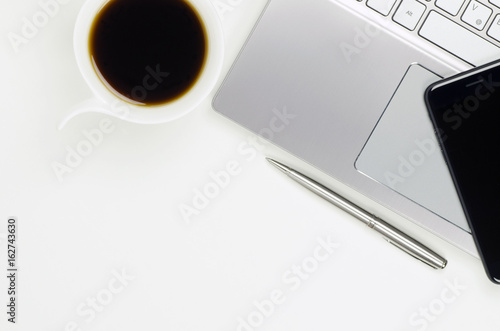 Close-up view of still life with laptop, smatter and pen next to a cup of coffee, isolated on white background with space for text