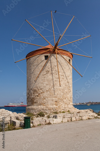 Windmill Papagiorg whit Vati in Rhodes harbor. Old defensive stands and windmills. Wharf harbors  boats and sailing ships. Historic pier and beach.