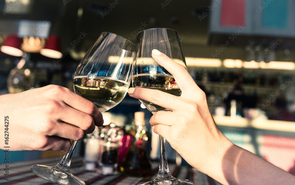 Young romantic couple with glasses of white wine on a date in a cozy Italian restaurant. Leisure, drinks, people and holidays concept - happy man and woman clinking glasses.
