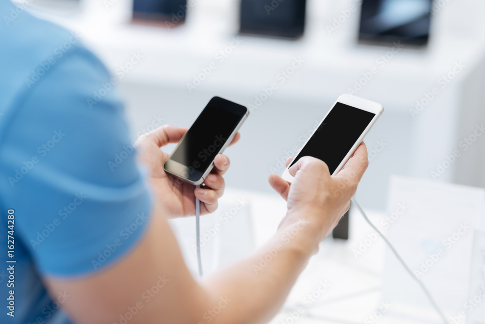 Close up of shopper comparing two phones at store Close up of shopper comparing two phones at store